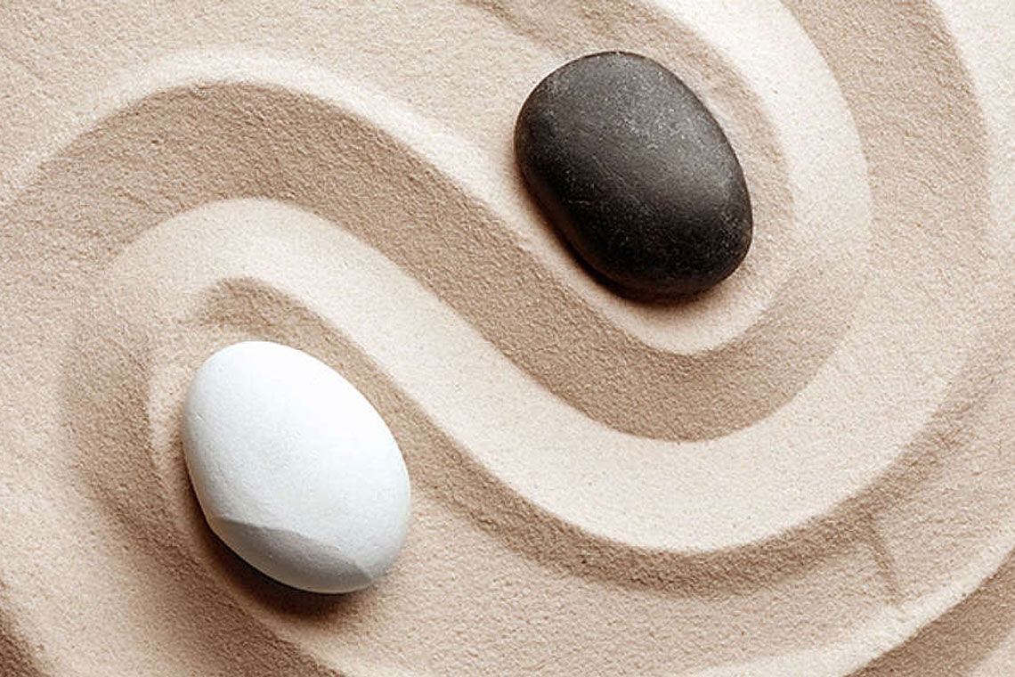 Ying und Yang in Form zweier Steine im Sand