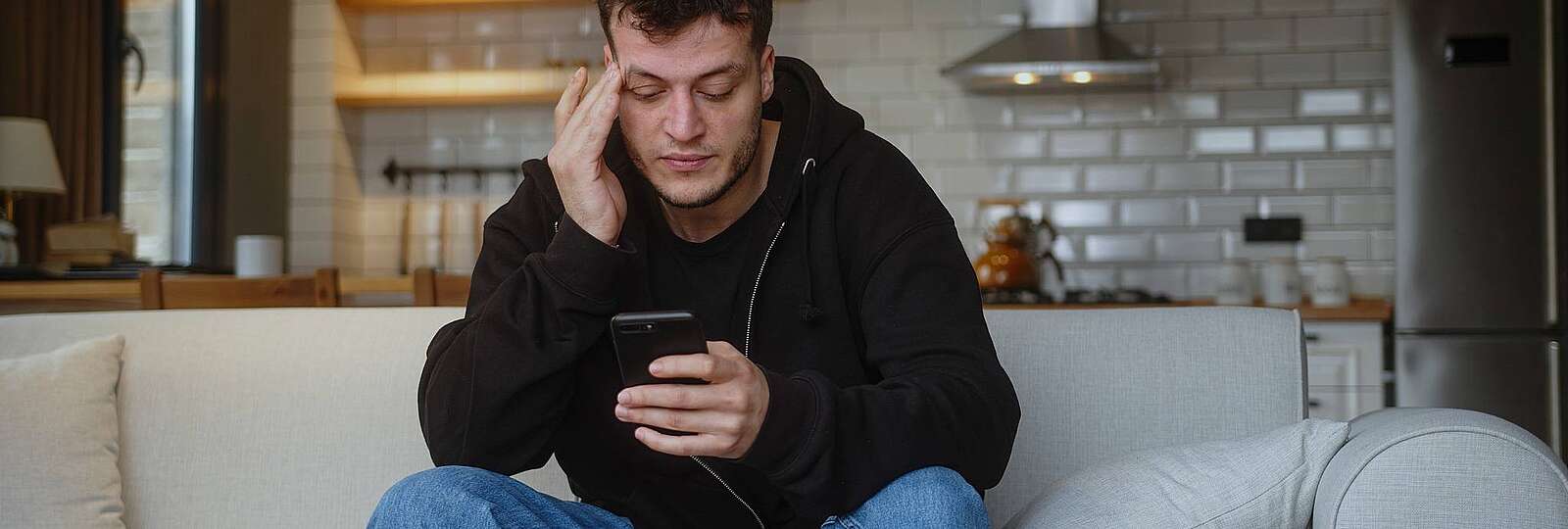 Ein mann schaut müde auf sein Handy