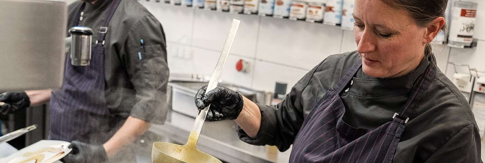 Ein Koch mit tätowierten Armen schaut in die Kamera