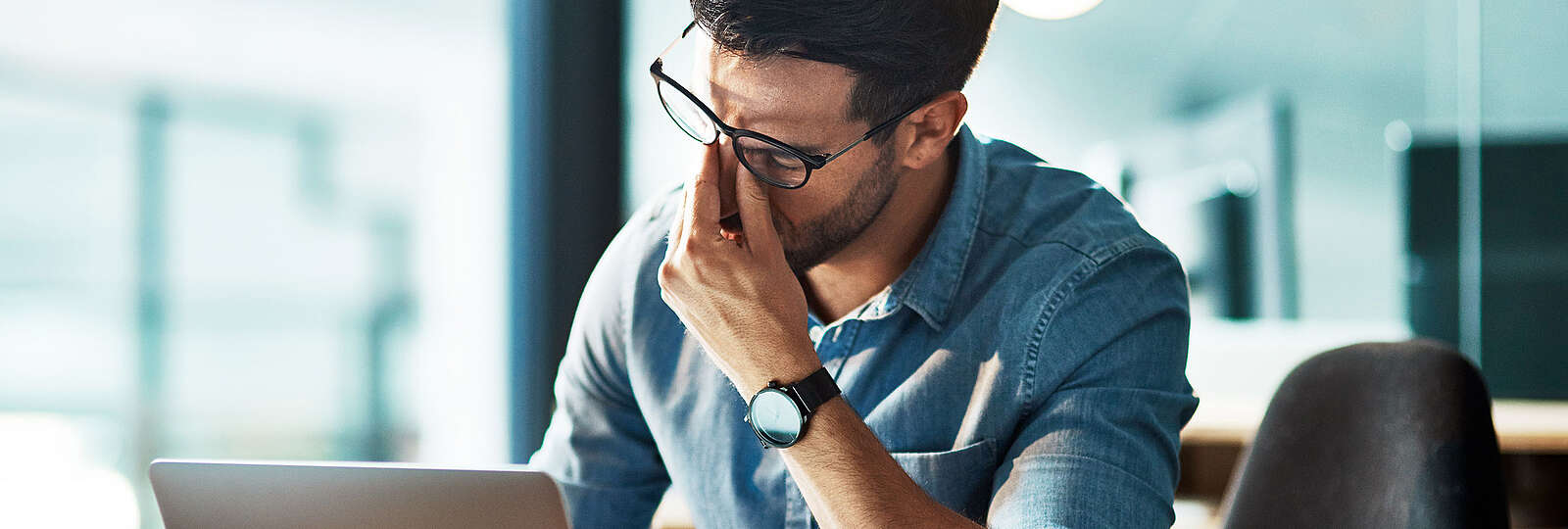Ein Mann mit Burnout fasst sich an den Kopf