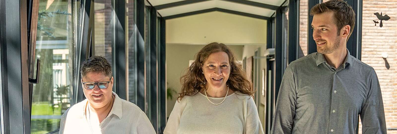 Eine Krankenschwester in privatem Dress mit verschrenkten Armen lächelt