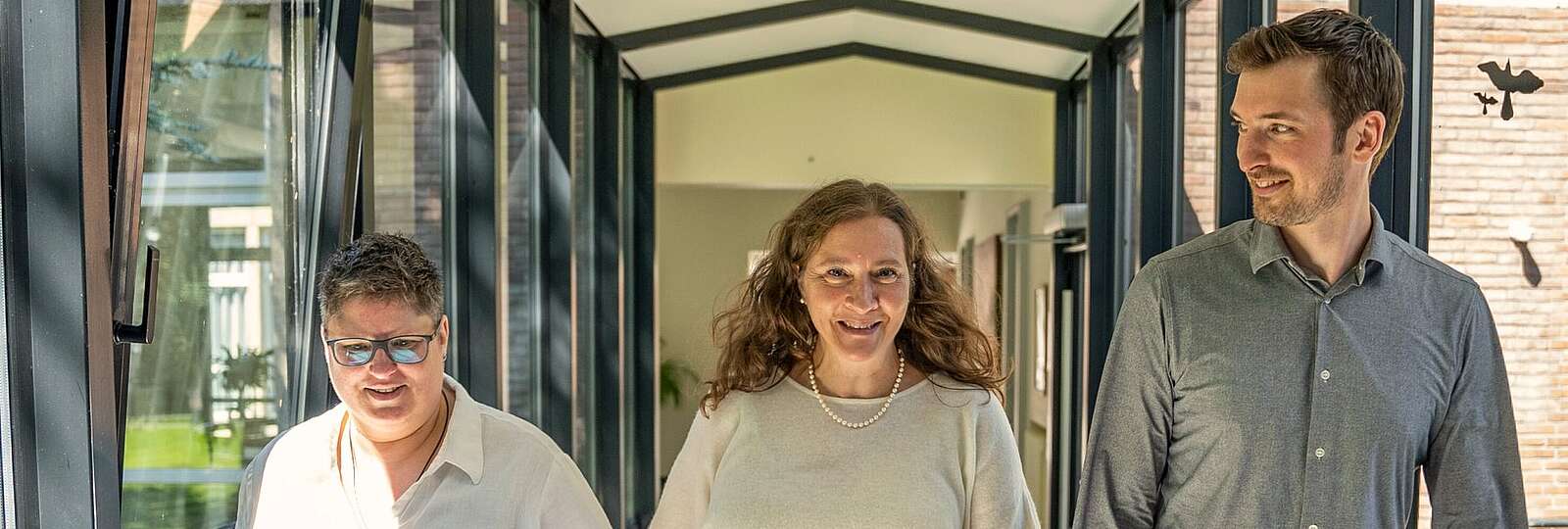 Eine Krankenschwester in privatem Dress mit verschrenkten Armen lächelt