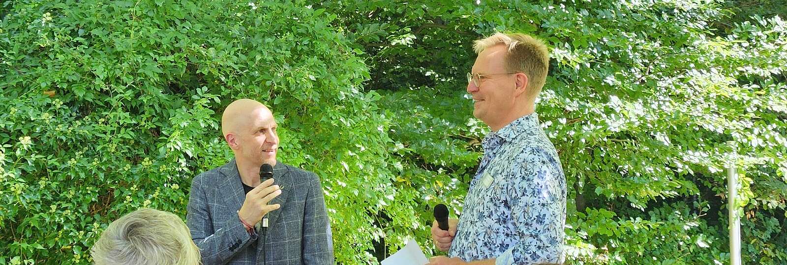 Dr. André Kümmel und Ulf Krause im Garten der Bonner Klinik bei der Eröffnungsrede mit Mirkos in der Hand.