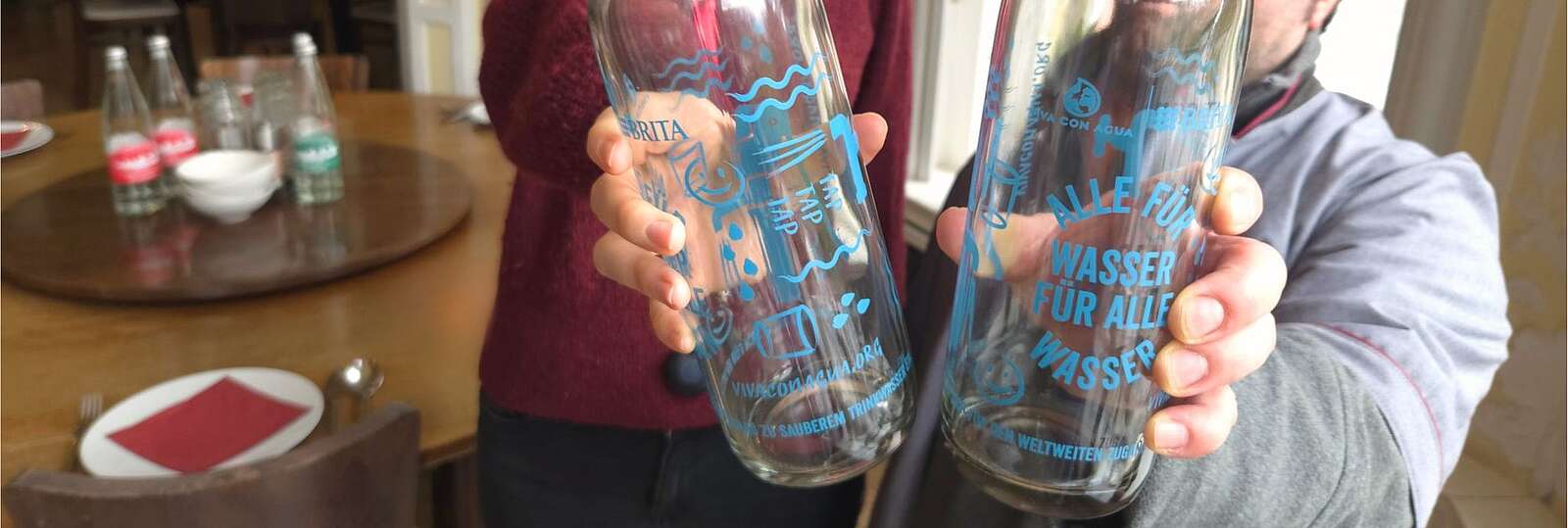 2 Personen halten eine Glasflasche in der Hand