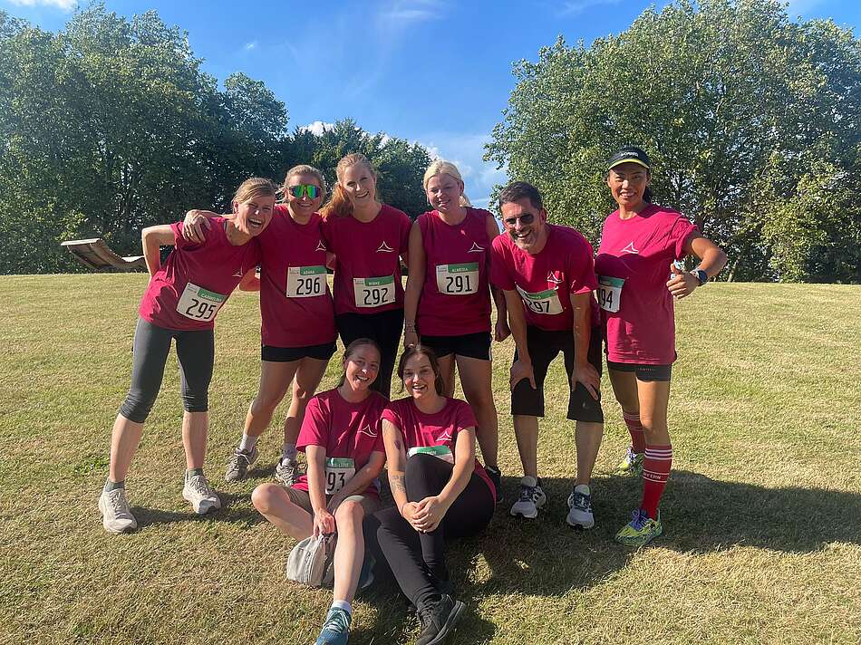 Acht Kolleg:innen in pinken Laufshirts beim Firmenlauf in Oberhausen.